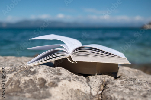 Canvas Print Reading open book at beach near the sea during summer vacation