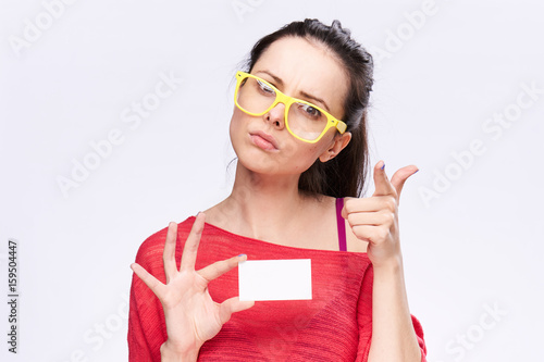 Woman in glasses and holding a business card on a light background