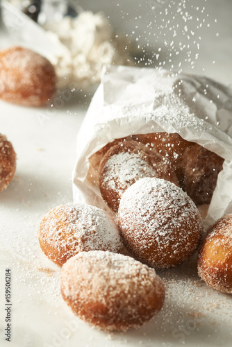 Doughnuts spilling out of bag with powdered sugar photo