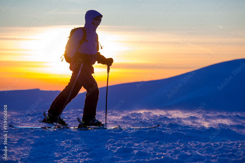 A skier is climbing the mountain ridge, snow, sunny day, in Carpathian mountains, skitouring in  Ukraine, beautiful sunset