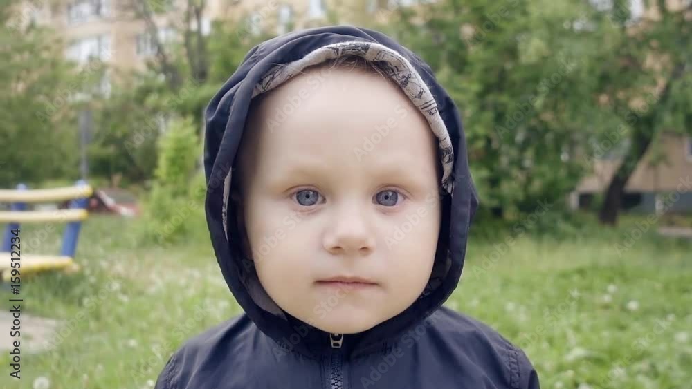 pretty child of two years walks in the yard and looking around the beautiful blue eyes. Dressed in comfortable clothes with a hood pretty child of two years walks in the yard and looking around the beautiful blue eyes. Dressed in comfortable clothes with a hood