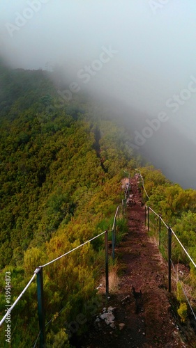 Path leading down a dark and foggy mountain during hiking in Madeira, Portugal