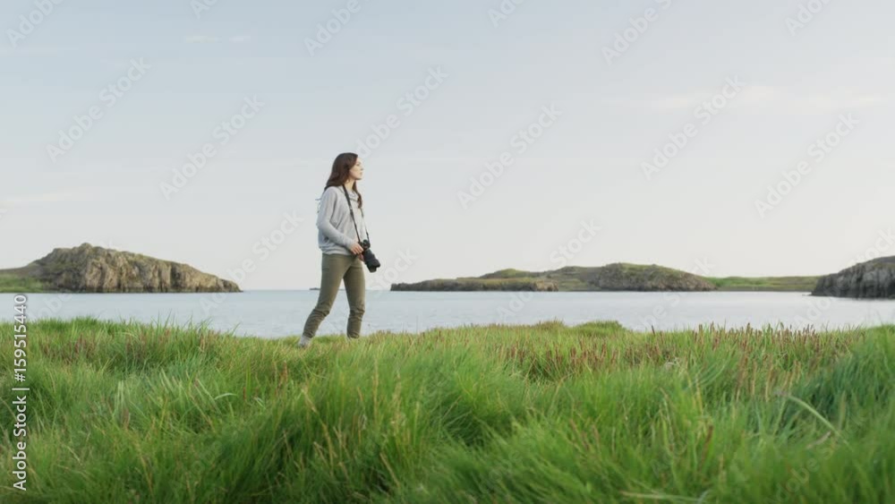 Wide panning shot of woman photographing near river. Borgarnes, Snaefellsnes, Iceland
