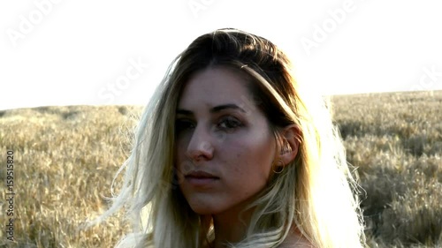 Beautiful blond woman in a red dress, on a wheat field at sunset