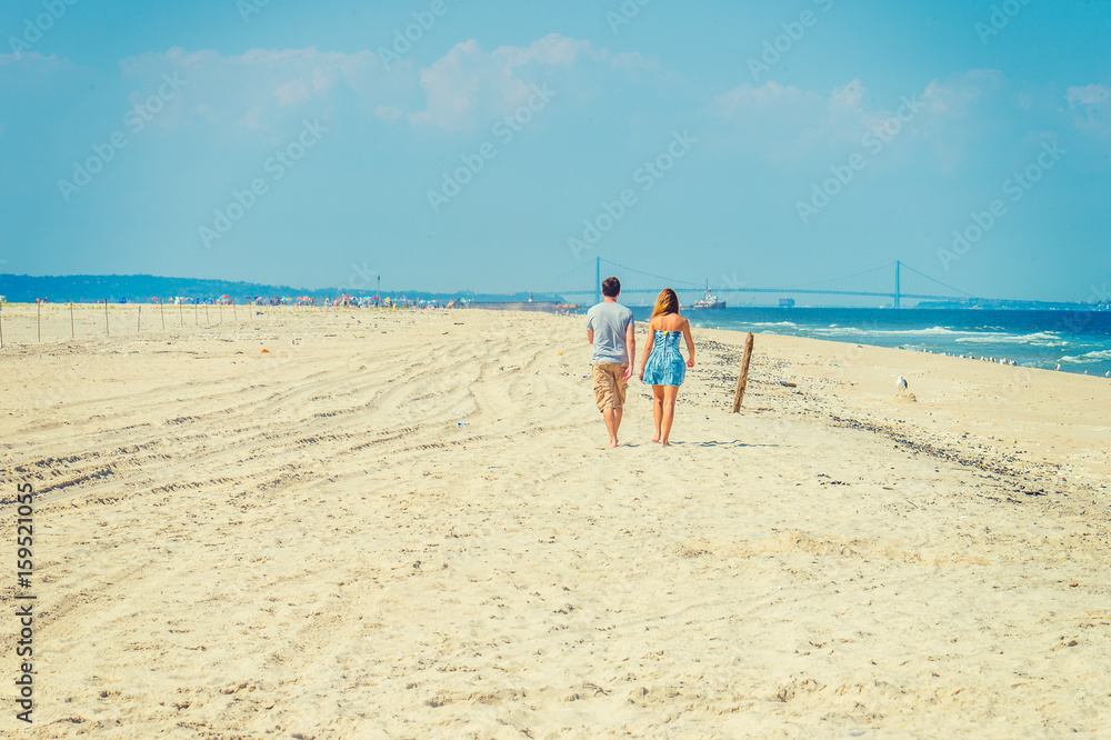 Young American Couple walking, relaxing on the beach in New Jersey, USA