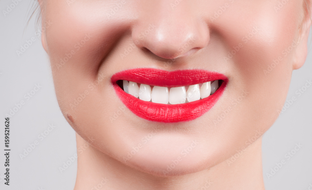 Fototapeta premium White teeth and red lips. Perfect female smile after whitening teeth.