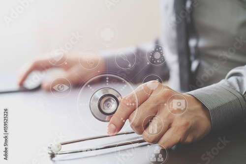 close up of smart medical doctor working with stethoscope and mobile phone on dark wooden desk in modern hospital