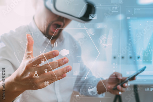 businessman wearing virtual reality goggles in modern office with mobile phone using with VR headset