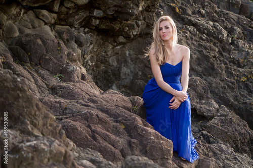 outdoor portrait of young beautiful woman in blue gown posing on natural background