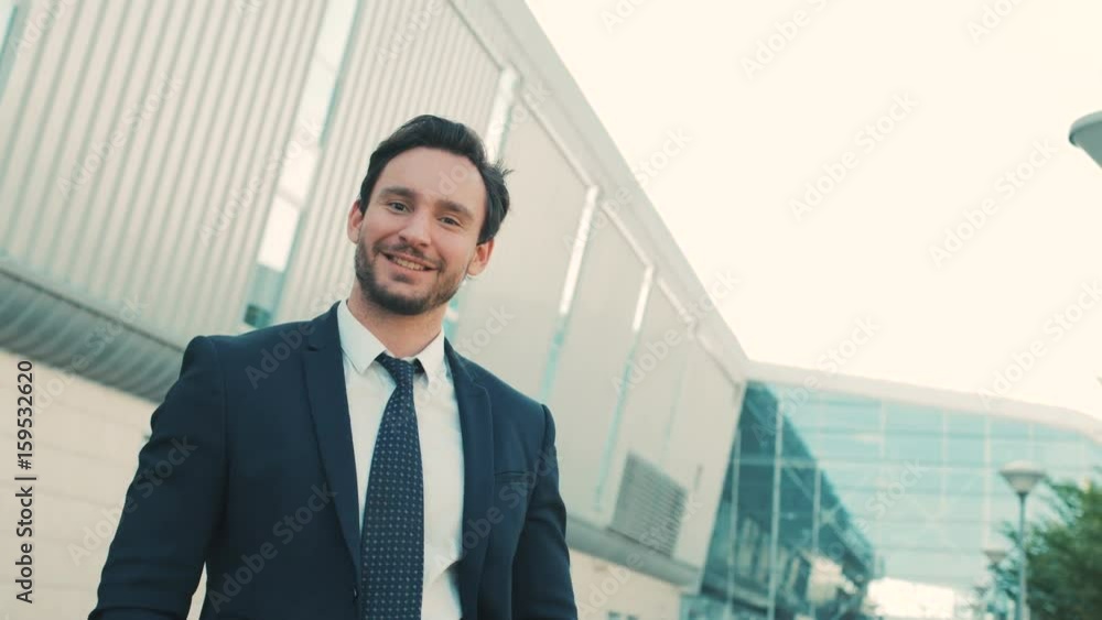 Attractive stylish businessman walking near office center building and taking off glasses and looking straight at the camera. close up. Portrait Attractive stylish businessman walking near office center building and taking off glasses and looking straight at the camera. close up. Portrait