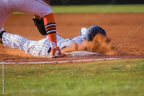 Baseball player sliding first base photo