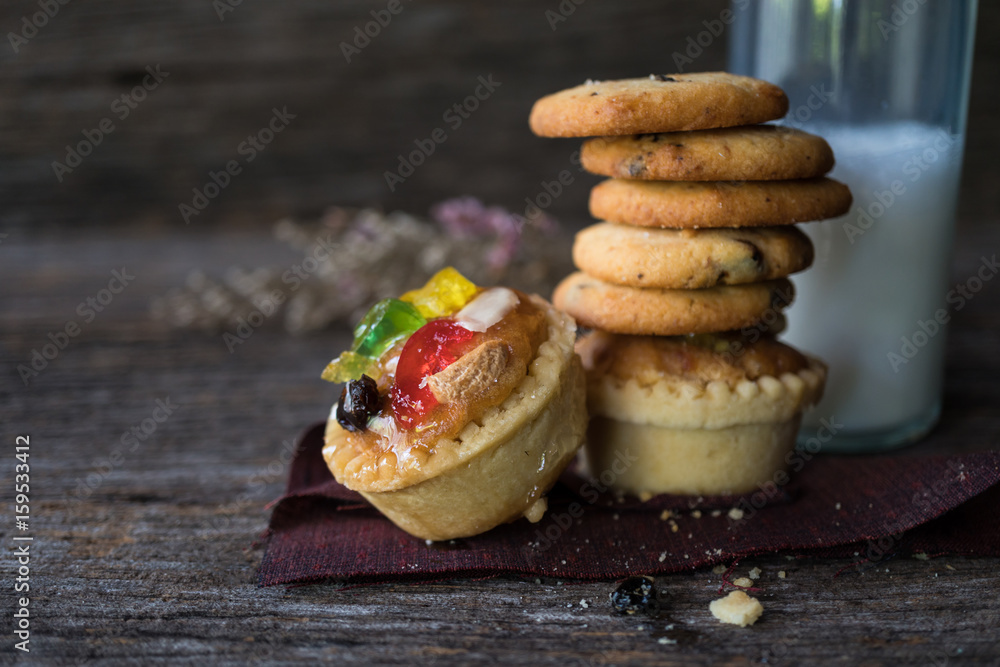 Homemade chocolate chip cookies and fruit tarts on wood background
