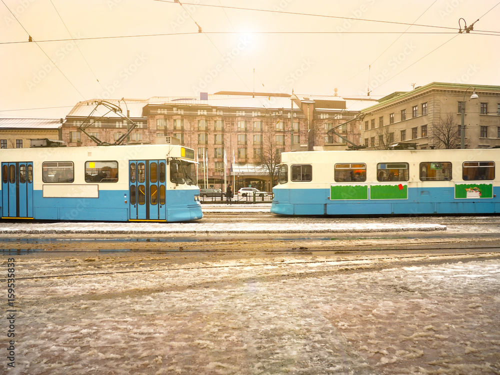 Two tram by in opposite directions with water season and gold light sky background Gothenburg city, Sweden.