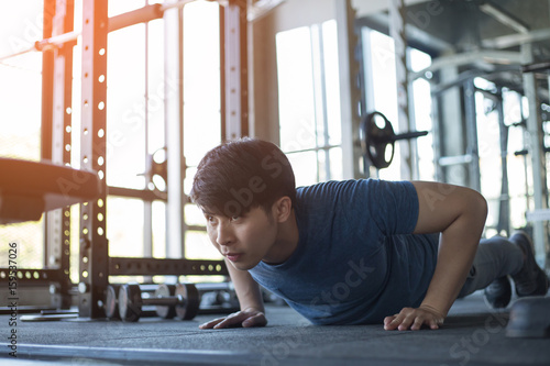 Młody Azjatycki mężczyzna ćwiczy w sprawności fizycznej gym z racy światłem