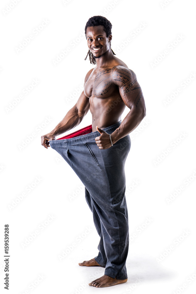 Shirtless black male bodybuilder has lost weight, wearing large pants and stretching them to see his progress Shirtless black male bodybuilder has lost weight, wearing large pants and stretching them to see his progress