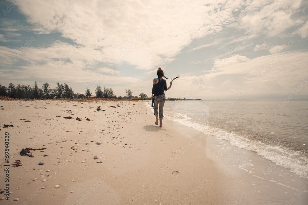 Naklejka premium beautiful boho woman walking by the shore line at the beach