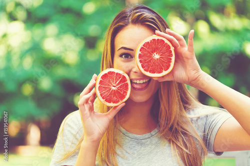 Happy young woman holding grapefruit