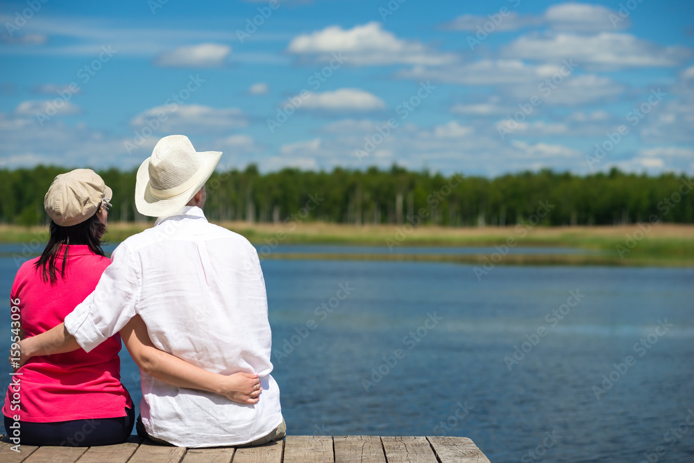 pair of lovers hugging, sitting on the shore of the lake pair of lovers hugging, sitting on the shore of the lake