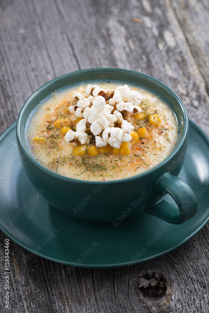 corn soup with popcorn in ceramic cup on wooden table, vertical, top view corn soup with popcorn in ceramic cup on wooden table, vertical, top view