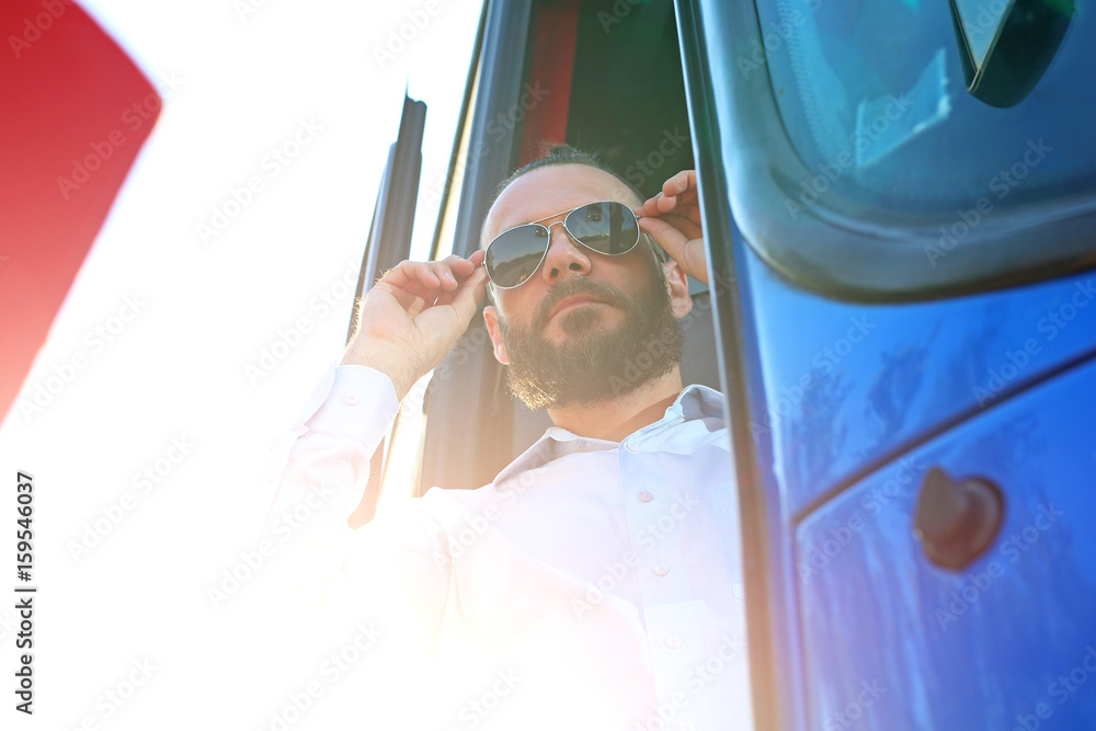 Kierowca autobusu poprawia okulary przeciwsłoneczne.Przystojny kierowca autobusu. - obrazy, fototapety, plakaty 