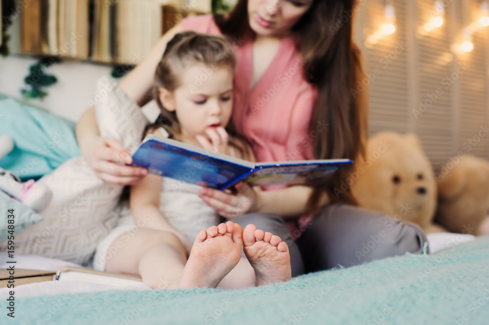 mother reading book to toddler daughter in bedroom for good night. Casual lifestyle capture of happy family at home mother reading book to toddler daughter in bedroom for good night. Casual lifestyle capture of happy family at home