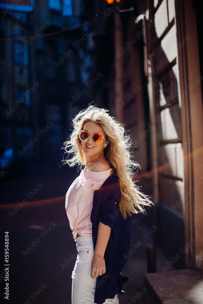 Fototapeta premium Look from behind at blonde woman posing in blue shirt