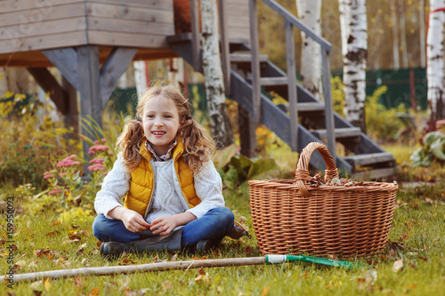 happy kid girl playing little gardener and picking leaves in autumn garden outdoor © mashiki