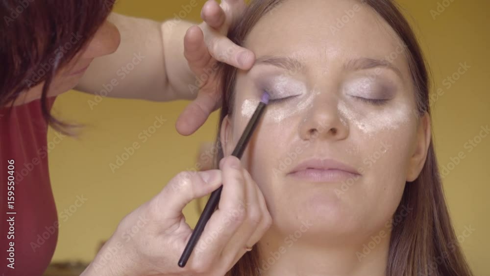 Makeup artist applying with brush eyeshadow on female eye, woman putting shadow powder on eyes, make up stage. Cosmetic beauty procedures. 4K ProRes HQ codec Makeup artist applying with brush eyeshadow on female eye, woman putting shadow powder on eyes, make up stage. Cosmetic beauty procedures. 4K ProRes HQ codec