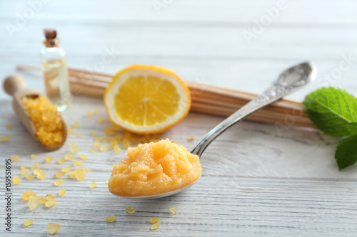 Spoon with orange scrub, sea salt and mint leaf on wooden table