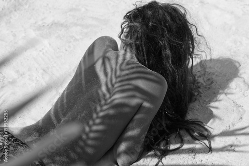 atrractive young girl lying on the beach with shadow on the back photo