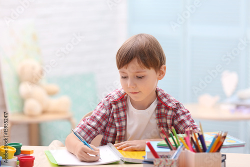 Cute little boy studying at...