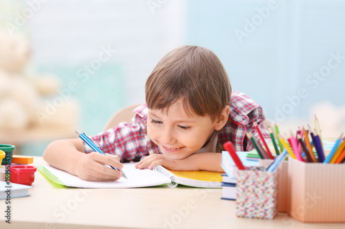 Cute little boy studying at...