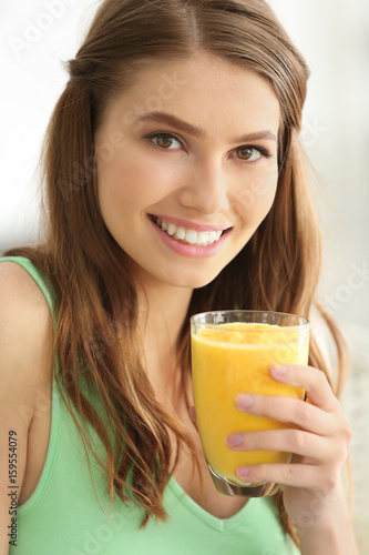 Weight loss concept. Beautiful young woman drinking healthy delicious smoothie on light background