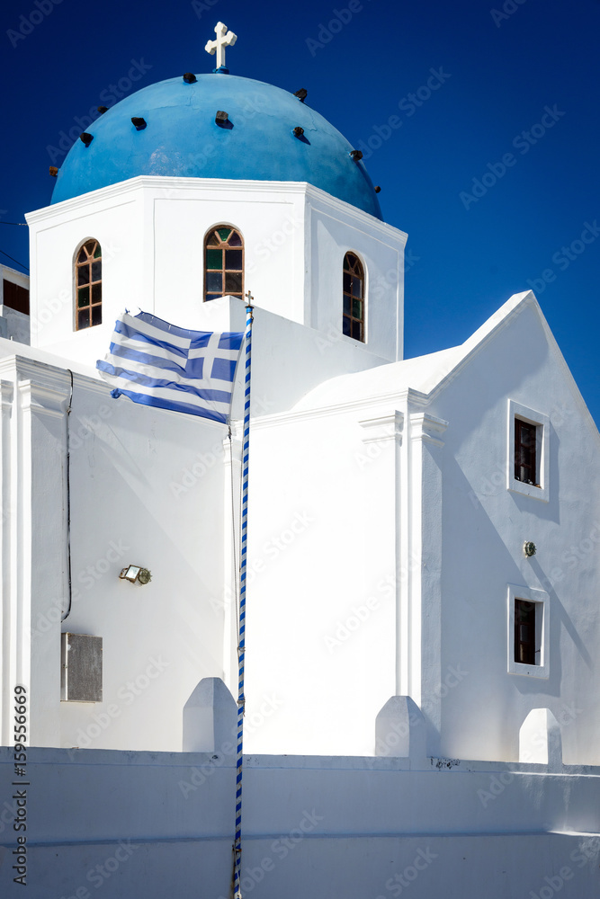 Church with blue dome and Greek flag in Imerovigli, Santorini, Greece