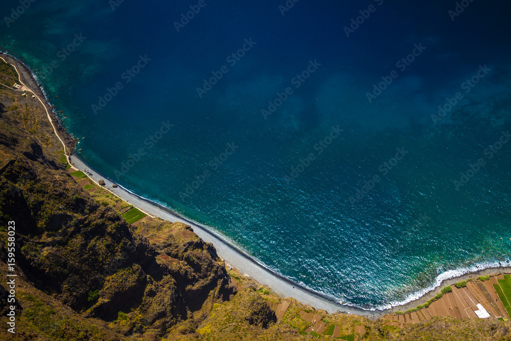 Madeira cliff landscape with azure water and blue sky with clouds