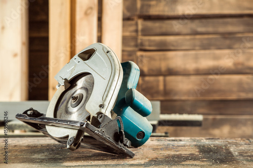 A modern green circular saw lies on a wooden table in the workshop. A close-up of a circular saw