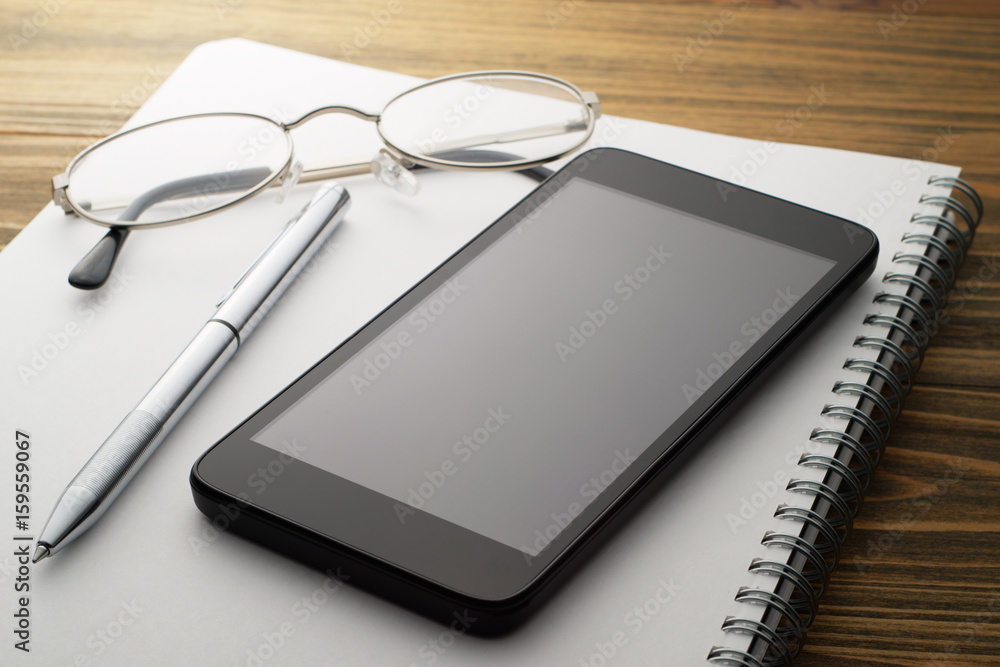 Smartphone and notebook on wood table.Smartphone, pen, glasses and notebook. Business desk.
Smartphone and notebook on wood table.Smartphone, pen, glasses and notebook. Business desk.