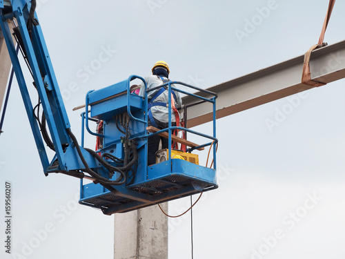 construction worker at construction site using lifting boom machinery