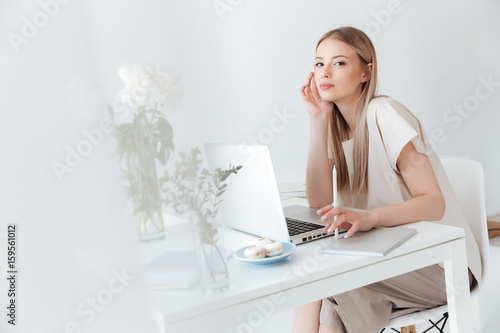 Serious woman sitting indoors using laptop