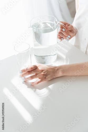 Cropped photo of lady sitting indoors near water jug