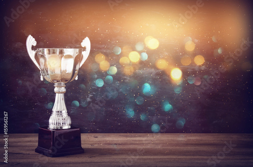 Wallpaper Mural low key image of trophy over wooden table and dark background