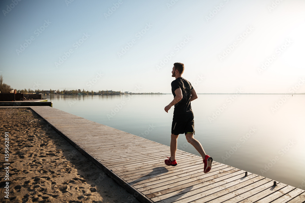 Back view full length portrait of a young sportsman running Back view full length portrait of a young sportsman running