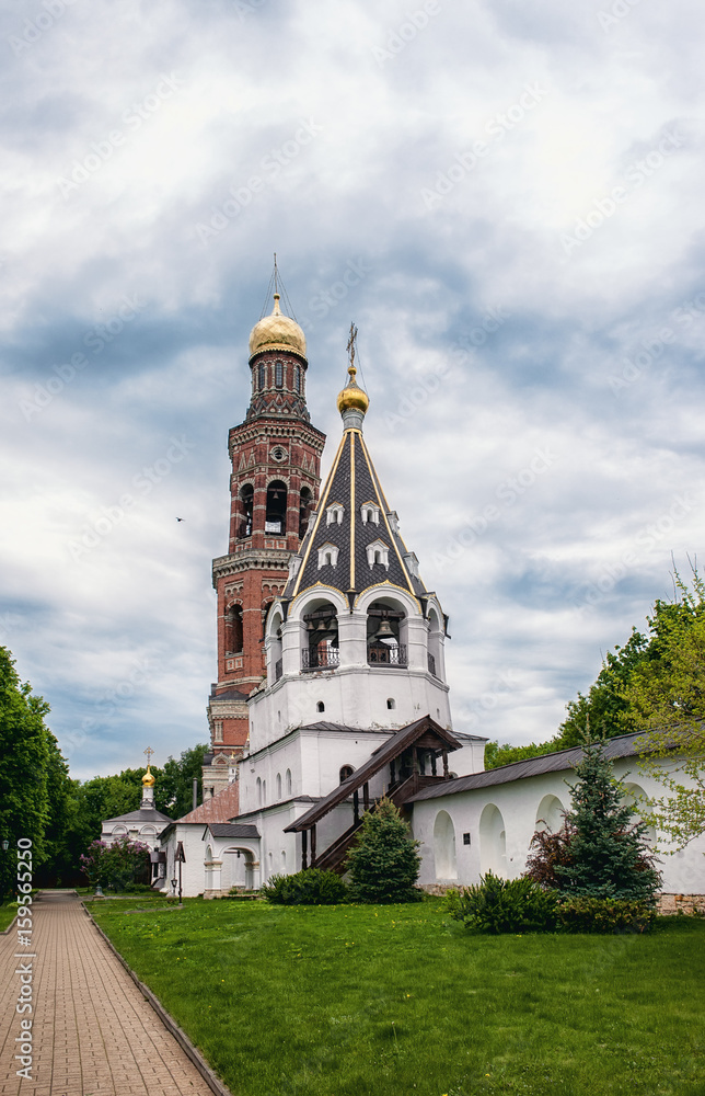 Ancient Orthodox Church with Golden domes and white stone bell tower in the monastery of the Ryazan region.