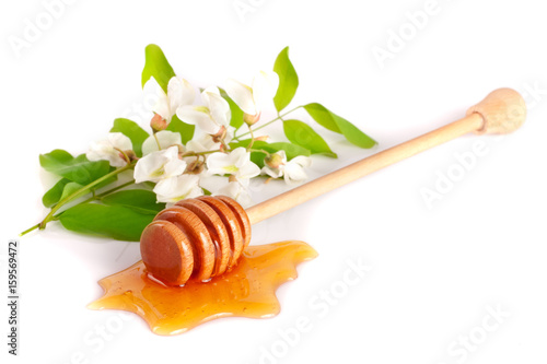 Honey stick with flowing honey and flowers of acacia isolated on white background