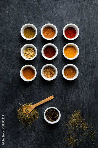 Overhead of Spice Bowls On Black Chalkboard with Scattered Herbs
