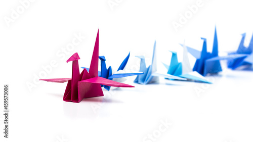 Leadership concept with red origami bird leading among blue.