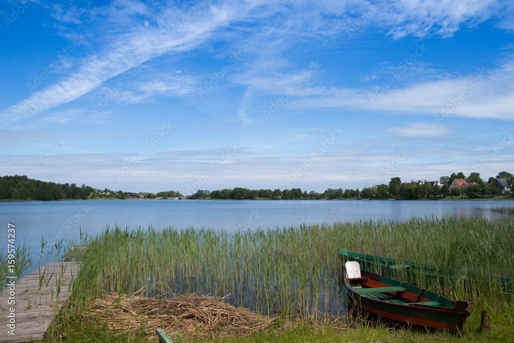 Concept of tranquil country life. Green boat in the lake on sunny summer day in Lithuania, Trakai. Excellent for flyer, post card, advertising, blog, instagram, calendar, notebook, wallpaper