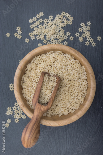 Red rice and olive wood scoop on black background of slate or stone. Vertical image photo