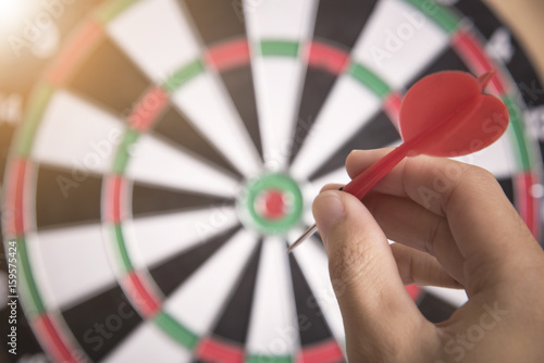 hand holhing red arrow target center of dartboard. concept business goal to marketing success.
