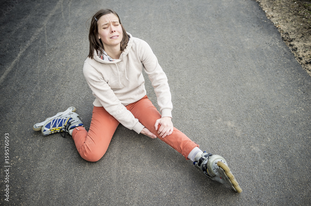 Cute woman fell riding on roller skates, and it really hurt his knee